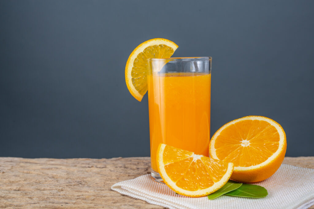 Suco de laranja em copo de vidro, com alguns pedações de laranja natural